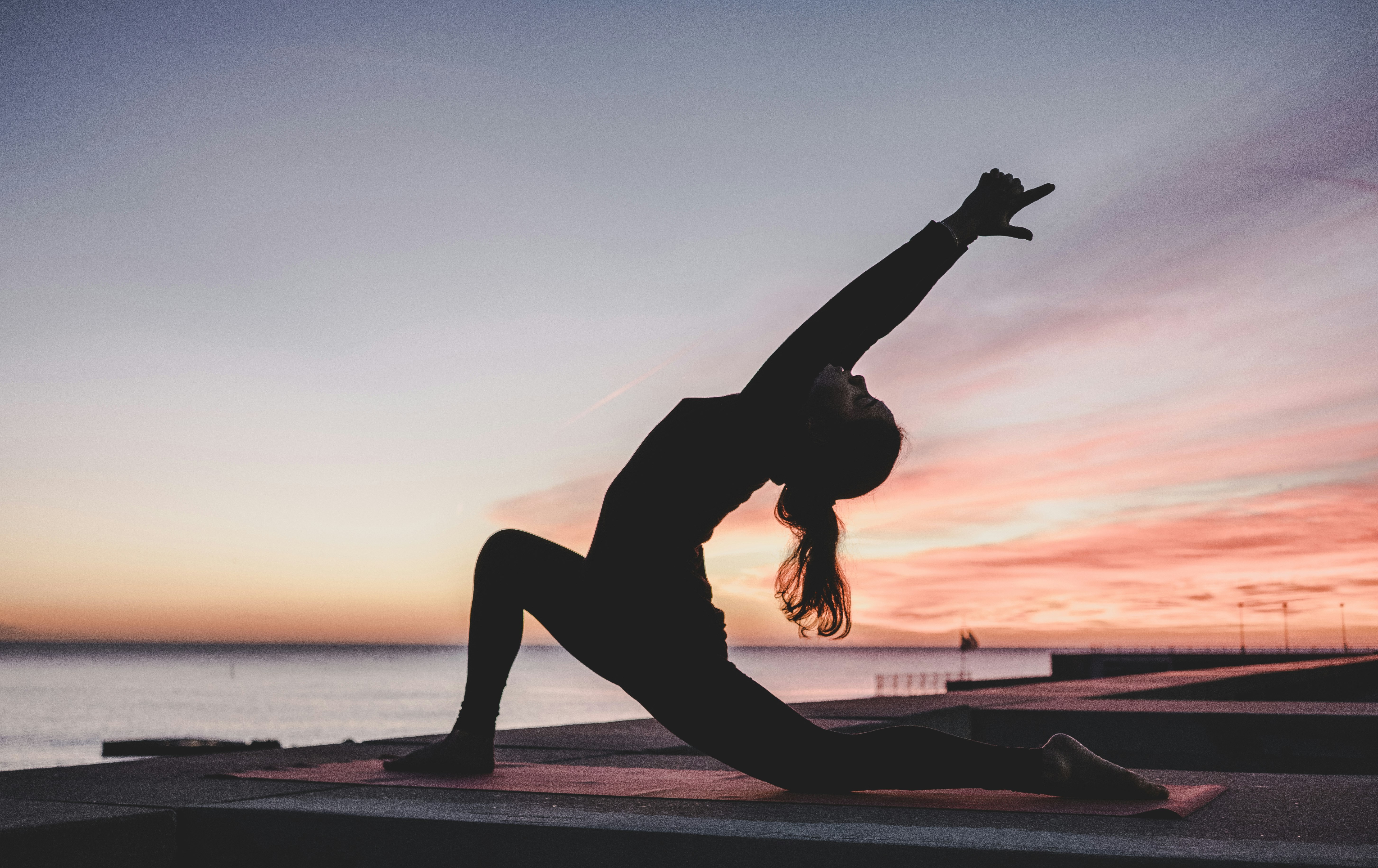 Woman practicing yoga at sunrise for ultimate health and longevity
